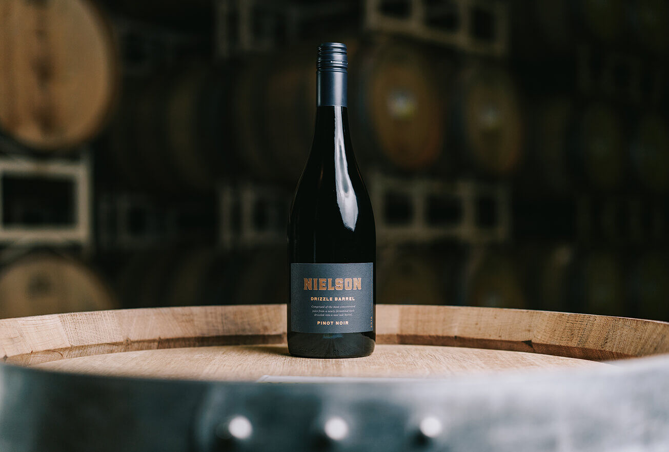 A Bottle of Nielson Pinot Noir placed on a barrel in their Santa Barbara wine cellar.